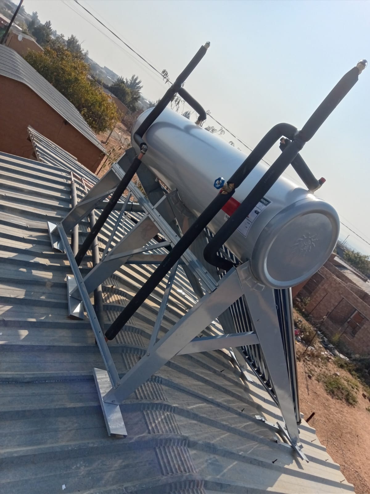 Solar geyser tank with insulated pipes on corrugated roof