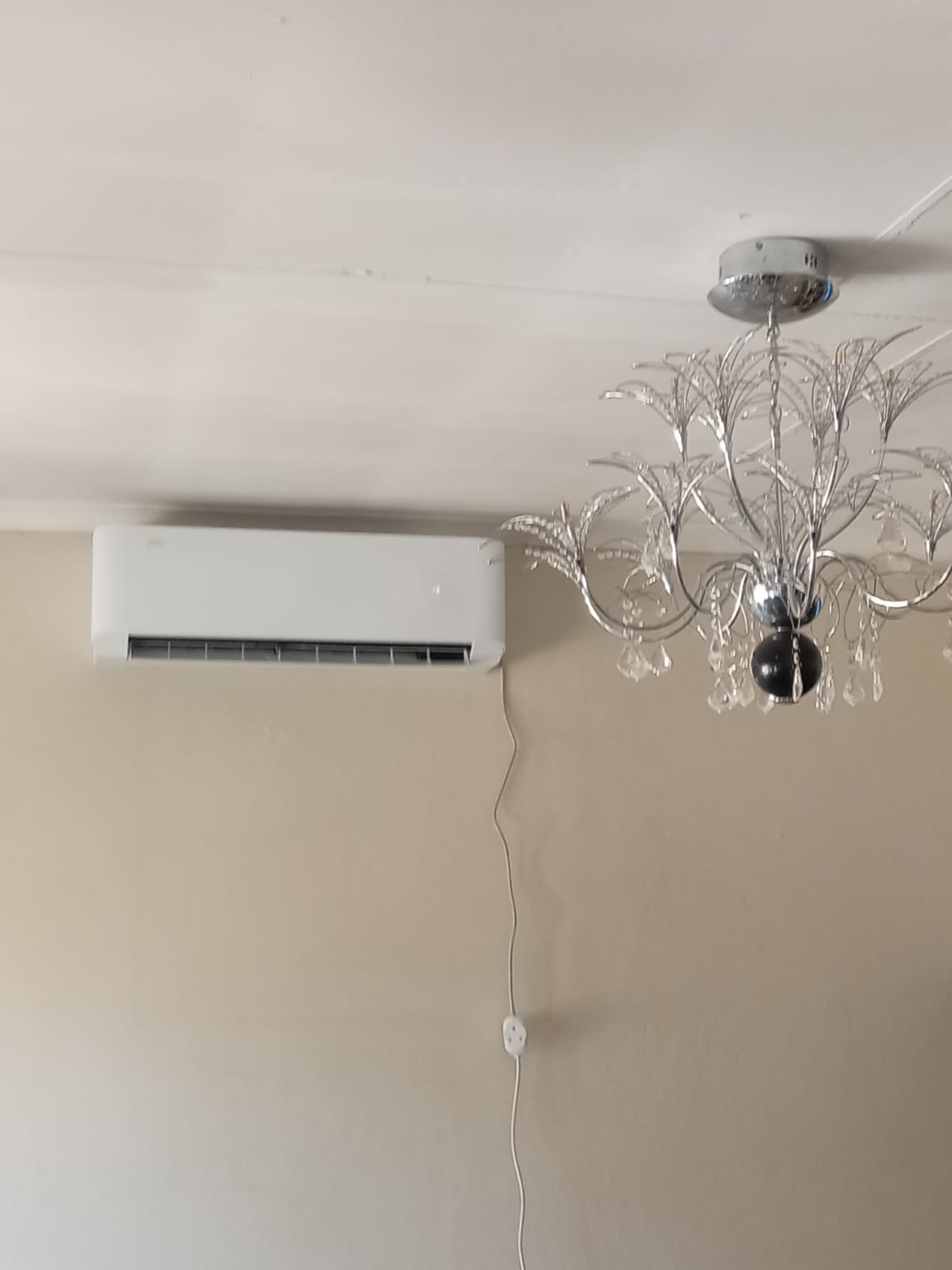 Split air conditioning indoor unit installed in living room with chandelier