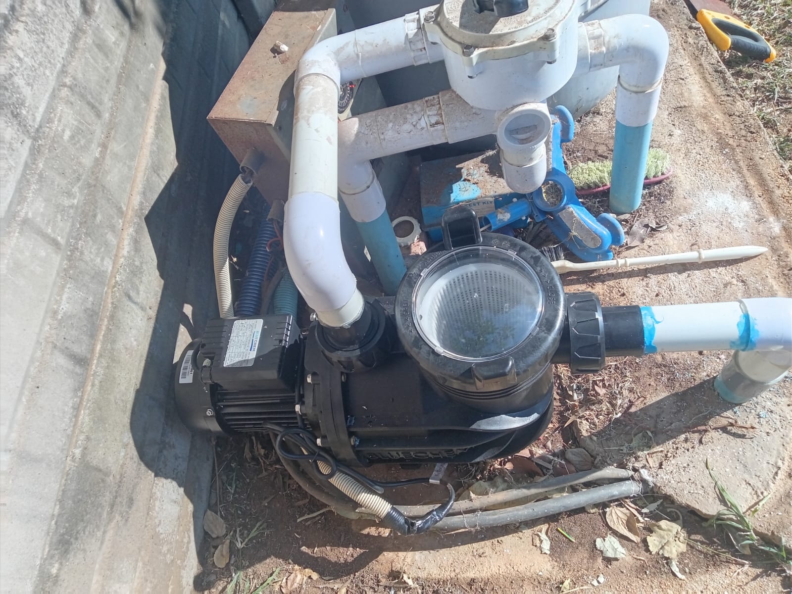 Pool pump motor close-up with PVC pipe connections and valves