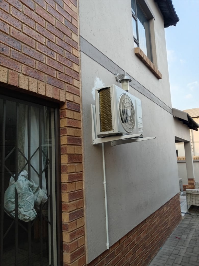 Air conditioning outdoor unit mounted on brick house exterior with trunking