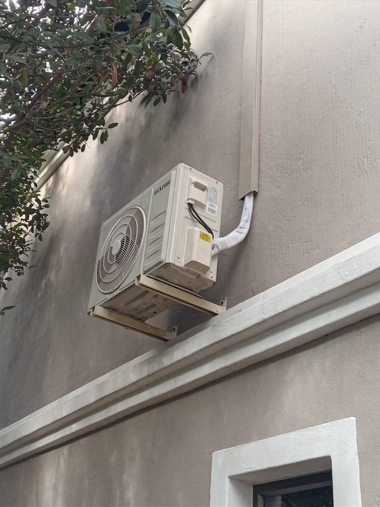 Goldair AC outdoor unit mounted on exterior wall with pipe connections