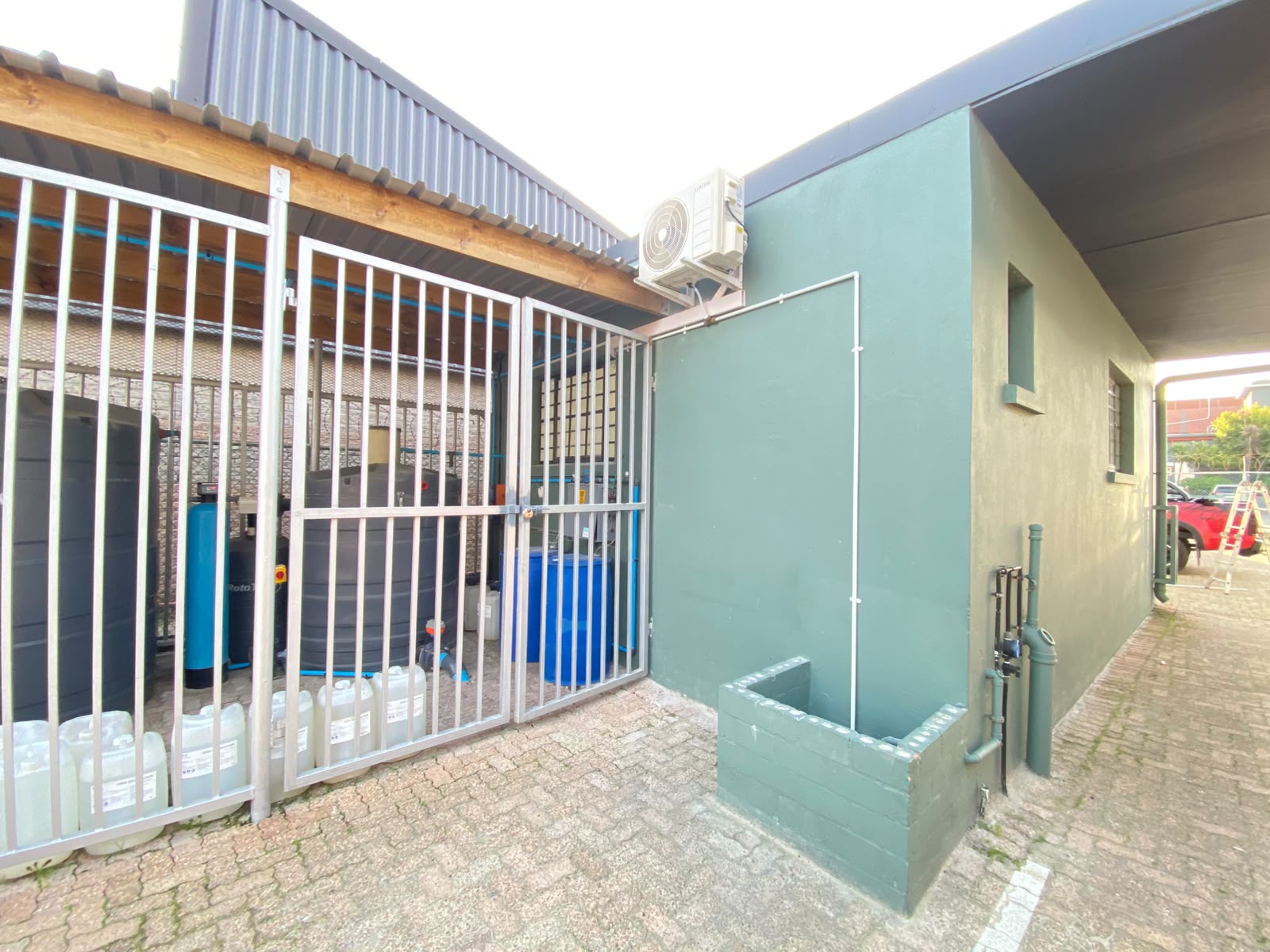 Goldair AC outdoor unit on commercial building with water storage tanks