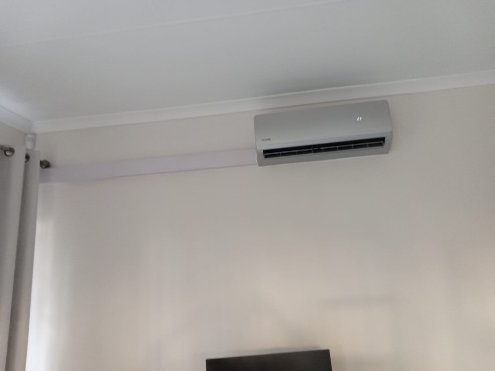 Split AC indoor unit with trunking installed in room above TV