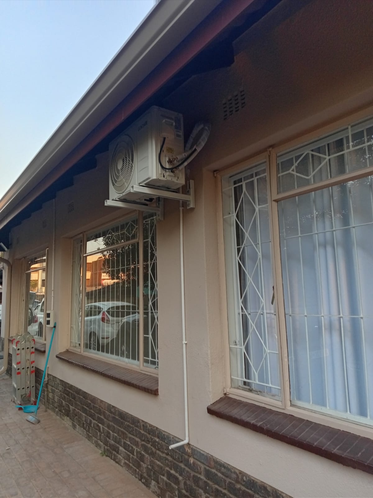 AC outdoor unit on residential house exterior with pipe trunking