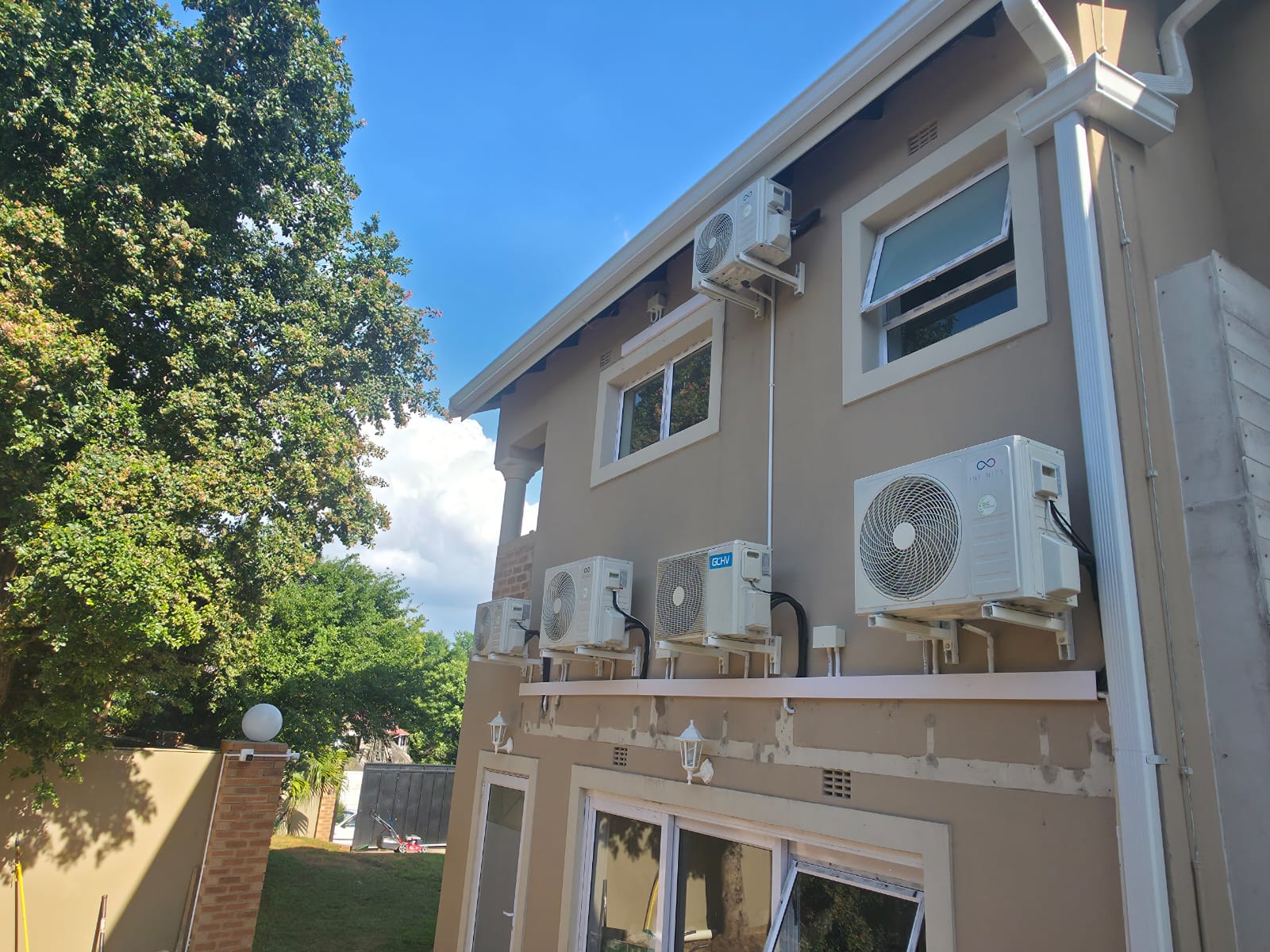Multiple AC outdoor units installed on two-story building exterior